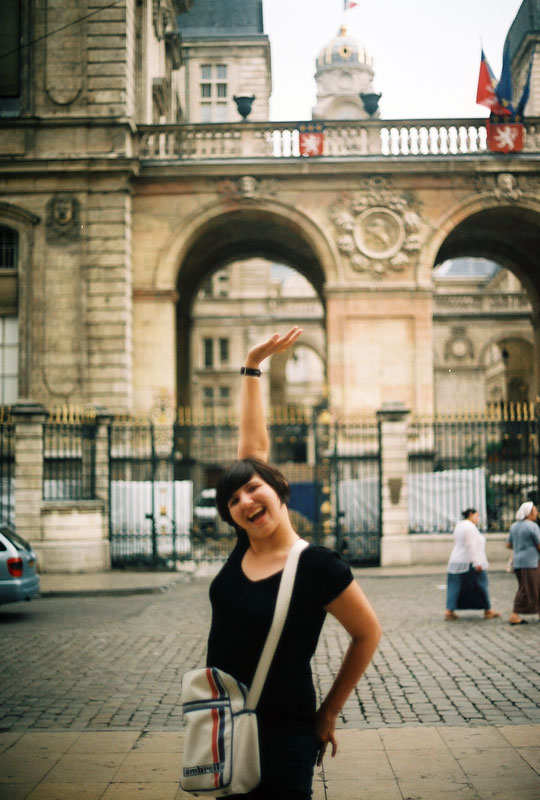 woman posing on brick path, with buildings in the background