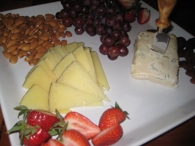 fruit and cheese is arranged on a plate on a table