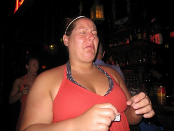 a woman in red top standing with a drink