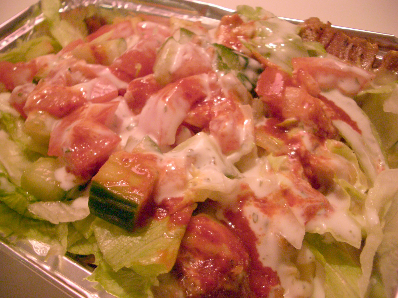 salad with meats, lettuce and sauce on it