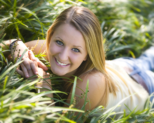the girl is laying in tall grass smiling