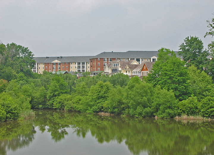 an apartment building is situated near a lake and many trees