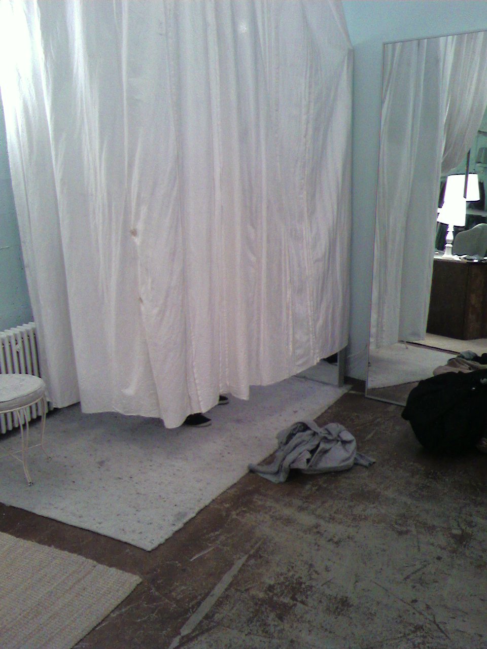 a white curtain is hanging next to a black suitcase