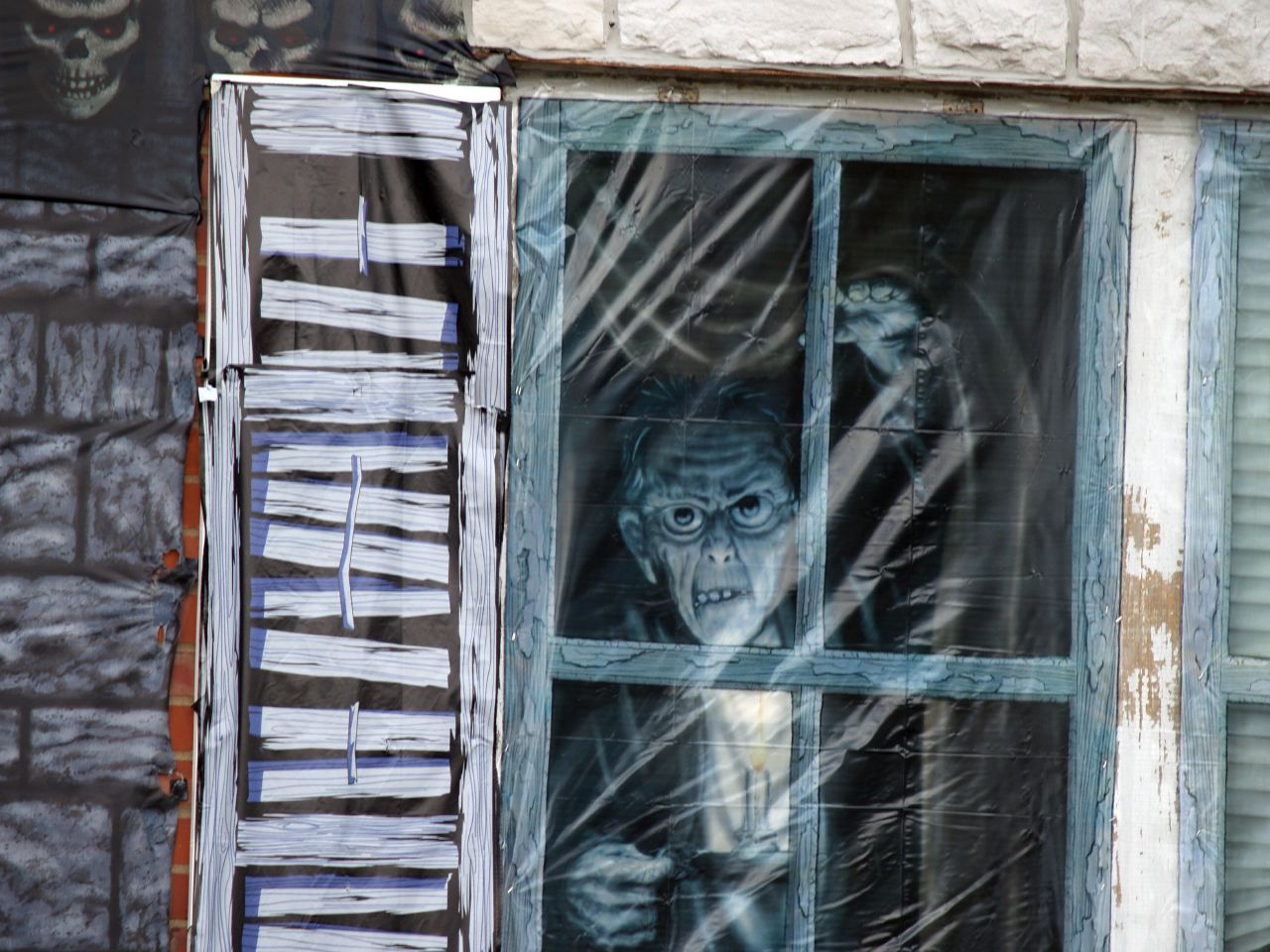 a skeleton doll is sticking out of a window in the street