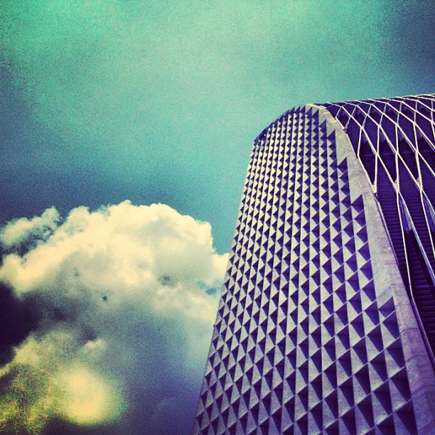 a tall building with white clouds and sky in the background