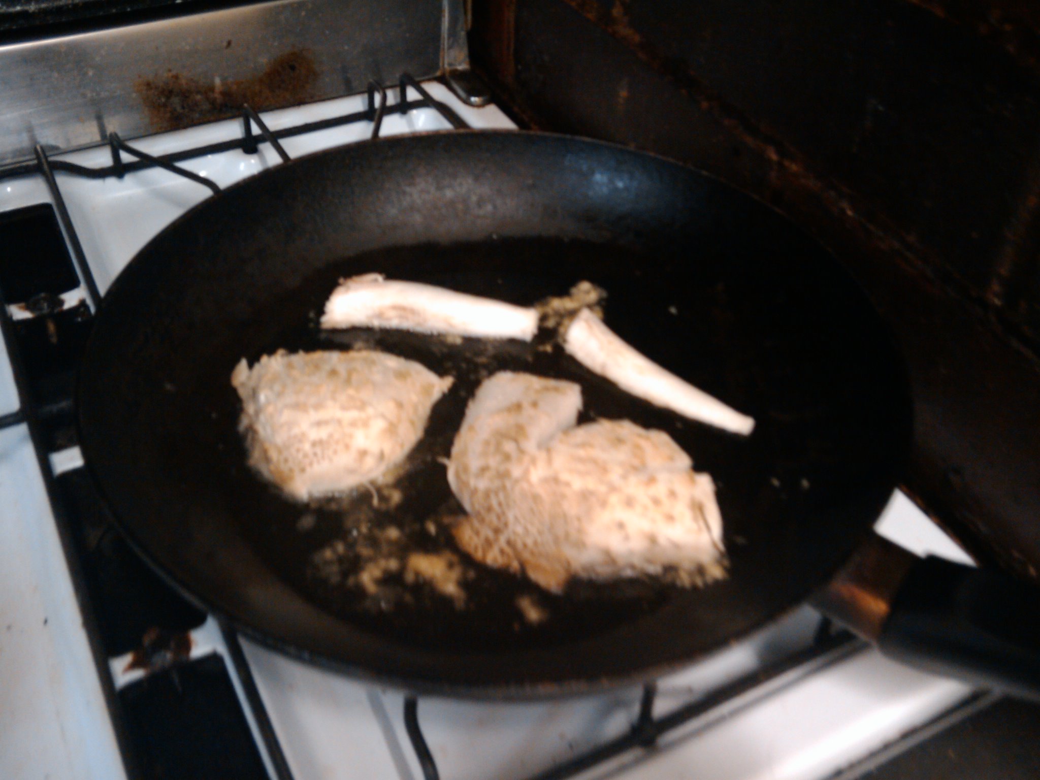 three fried chicken  in a frying pan on an open range