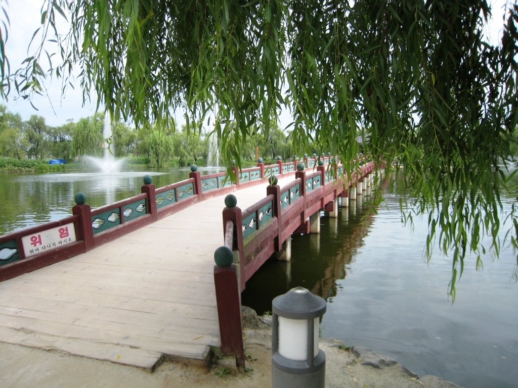 a red bridge over water with lots of trees around