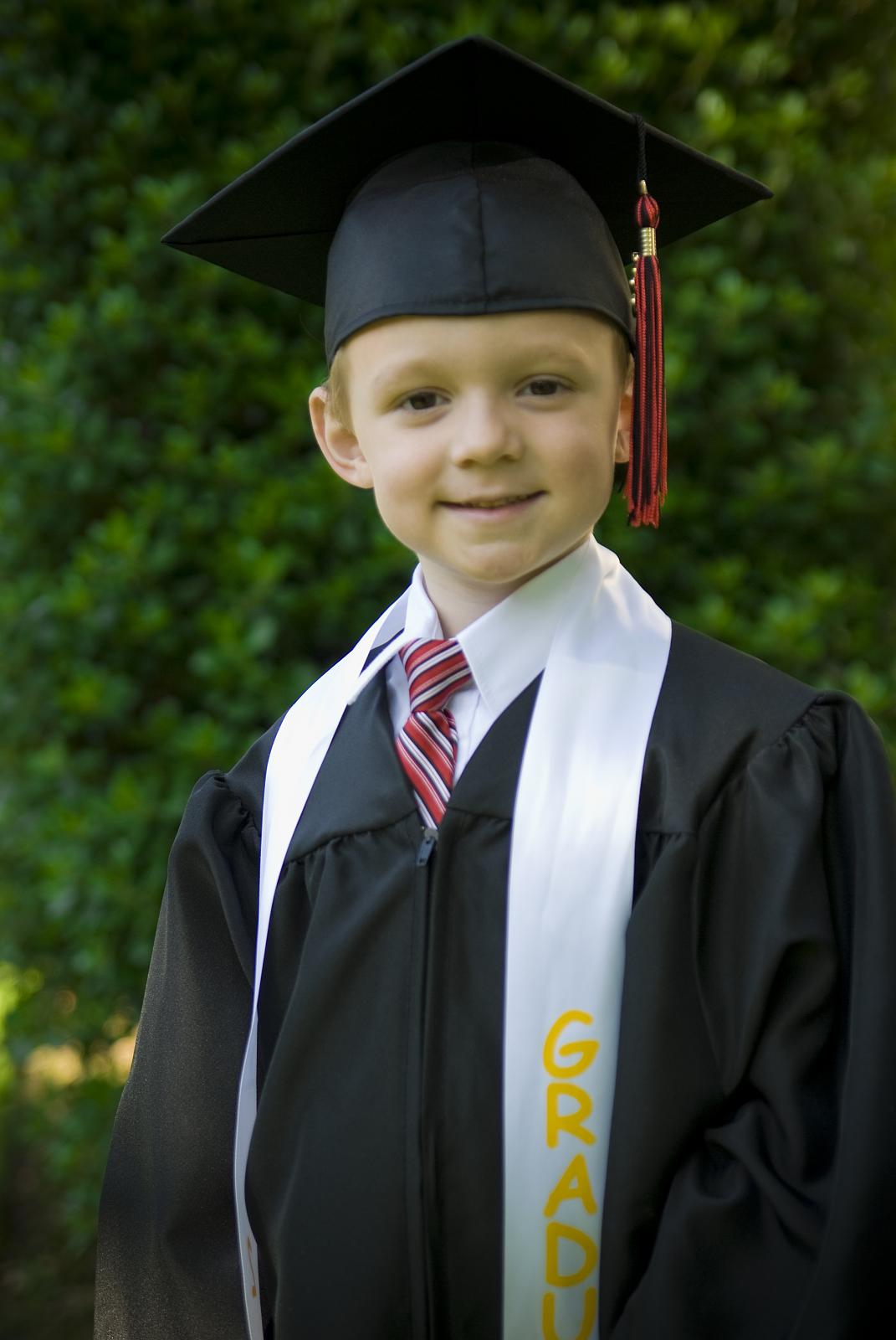 a little boy in a graduation gown and cap and tie