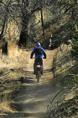a person riding a motorcycle on a dirt trail