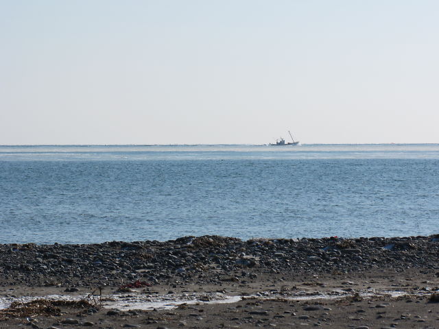 a small boat floats in the distance over a calm sea
