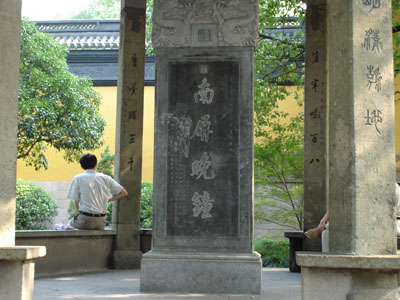 a monument with writing painted on it and in the middle of it people sitting on benches under the columns