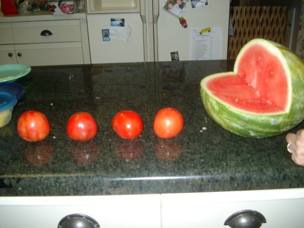 watermelon and tomatoes arranged on a black counter top