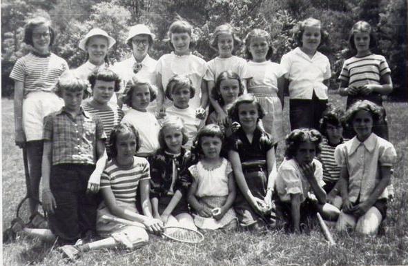 a group of young children sitting and standing in a field