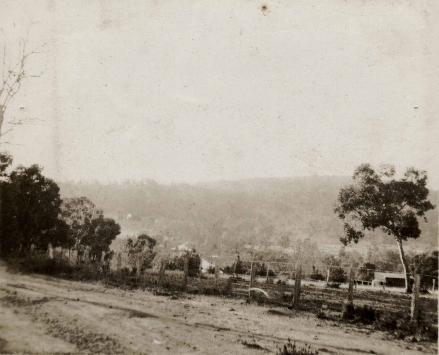 a old picture of an empty road going into a fenced off area