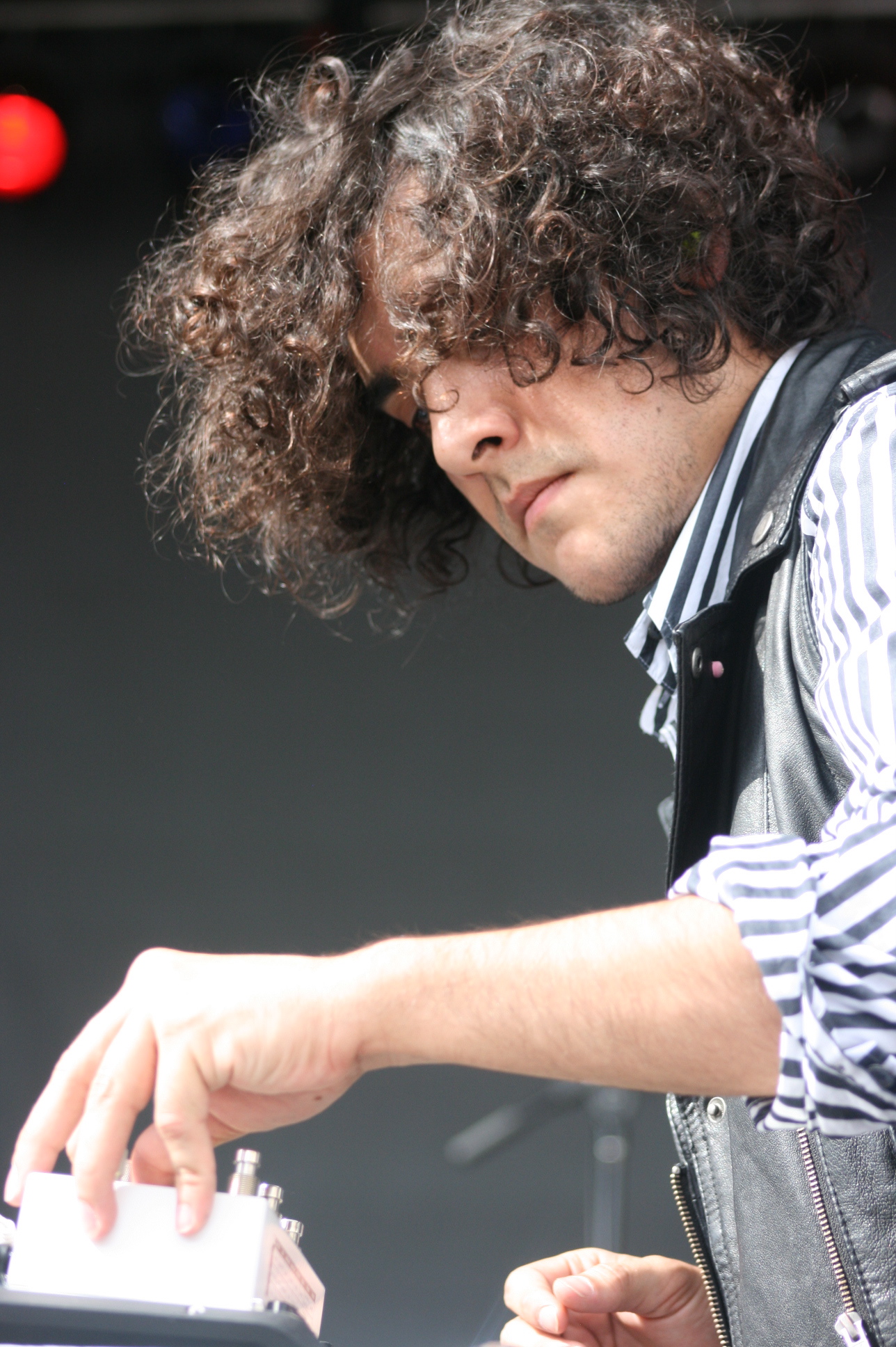 a young man plays piano while wearing a vest