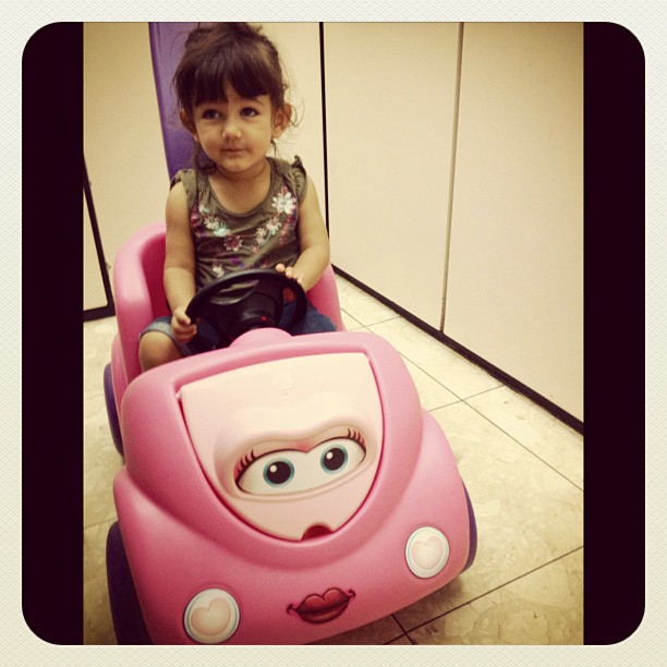 a young child riding a little pink car