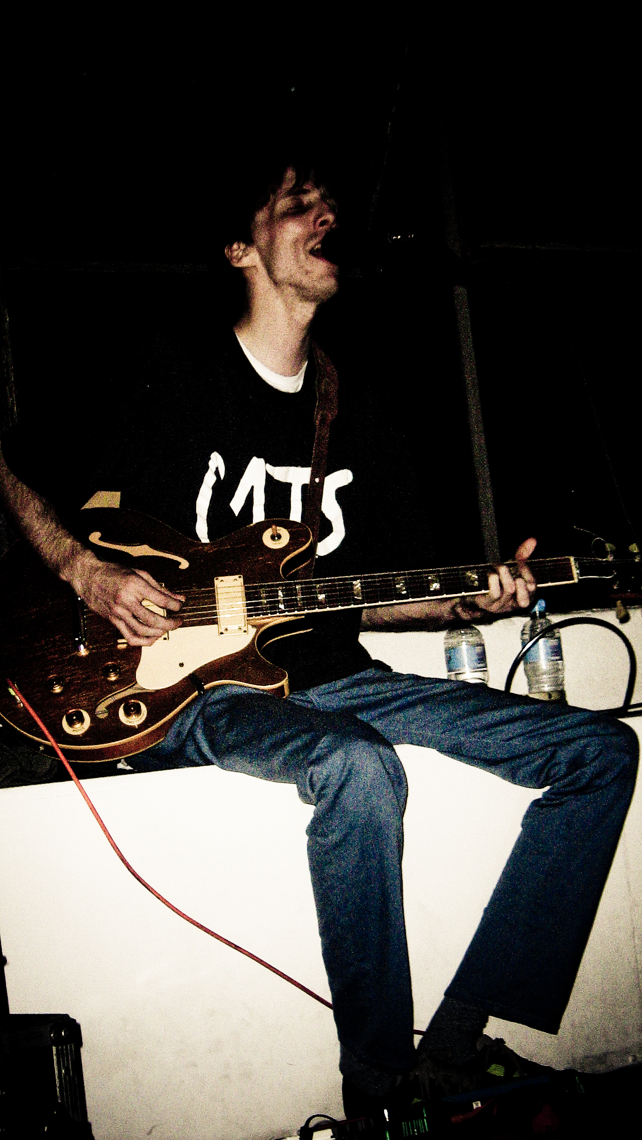 a man holding a guitar while sitting down