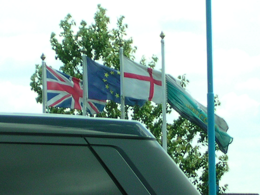 two flags in a parking lot next to a van