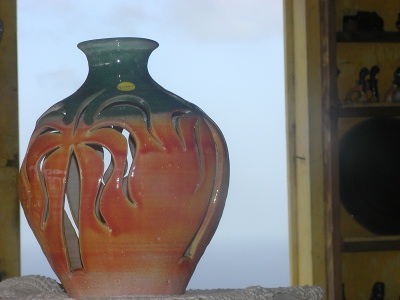 a large red and orange vase is sitting in front of the open bookcase