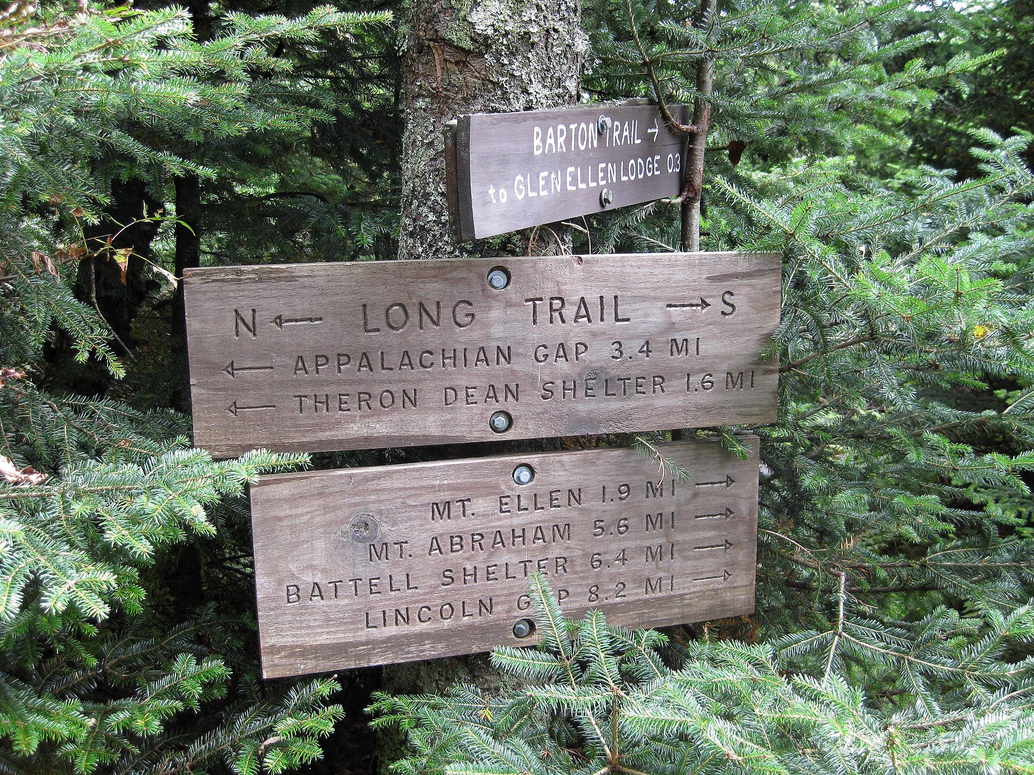 a wooden sign pointing in several different directions in the woods