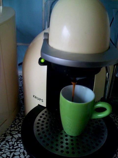 a cappuccino coffee maker with a green mug next to it