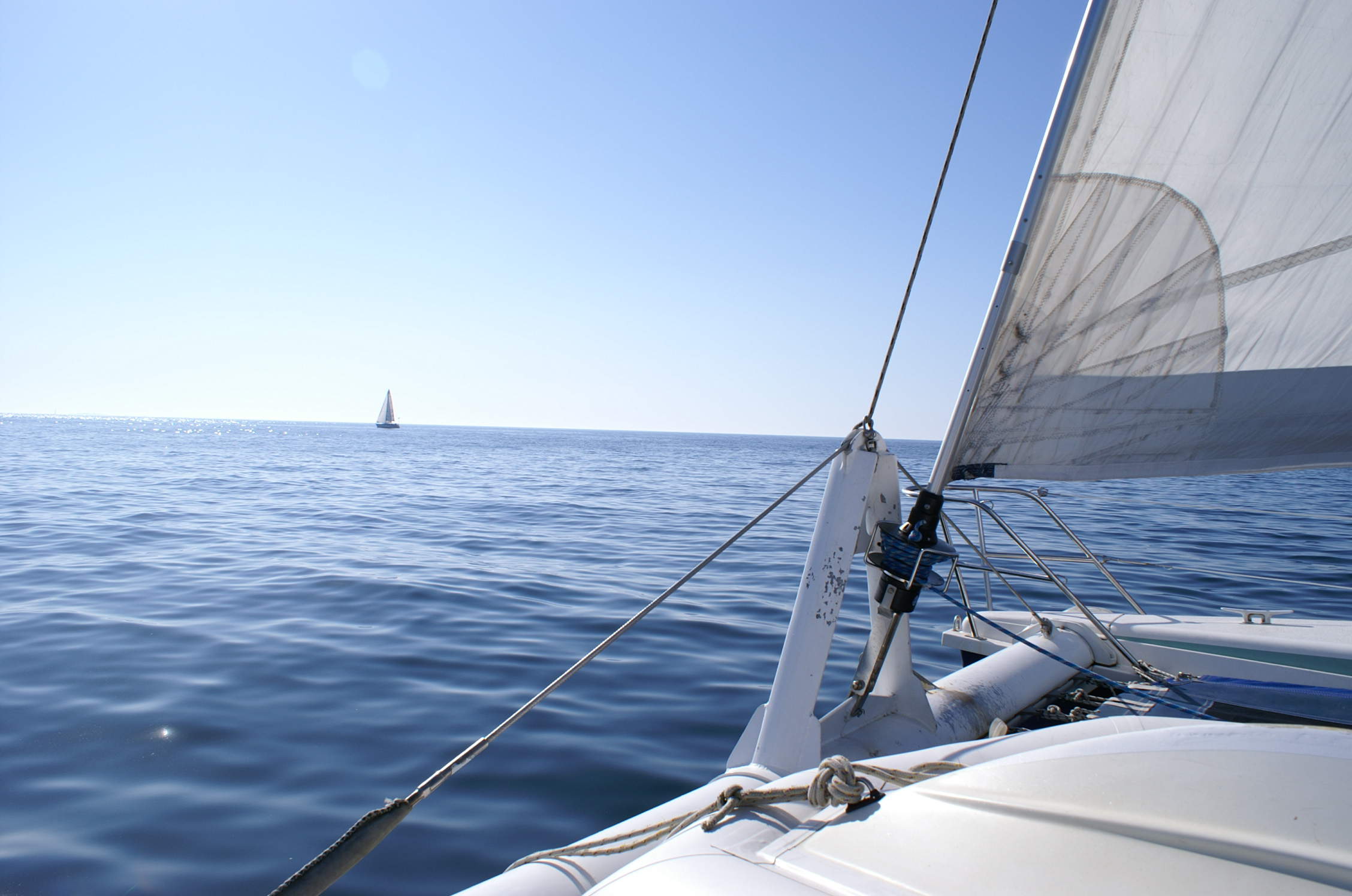 a sail boat sailing in the water near the shore