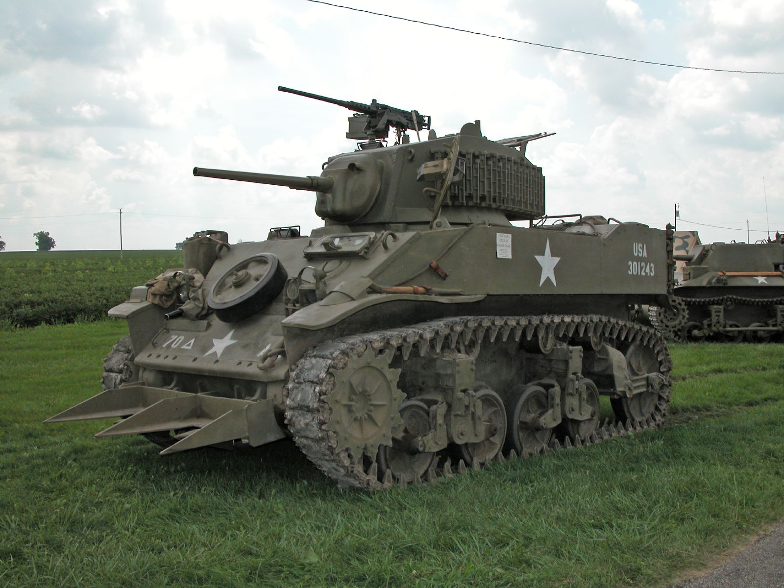 a tank in grassy field next to some other tanks
