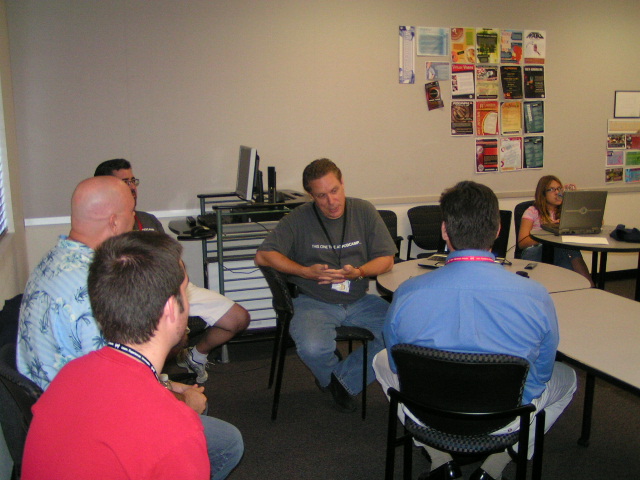 people sitting in a circle around a laptop in a small room