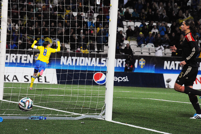 a soccer player tries to control the ball as the opposing goalie watches