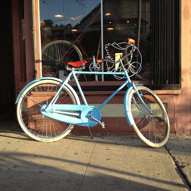 blue bicycle parked in front of window of store