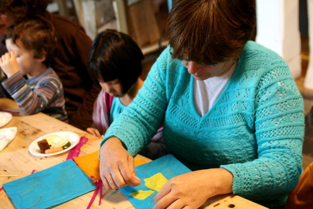 a woman makes crafts for her children at a table