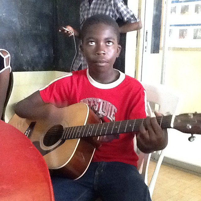 a boy is playing a guitar by the boy has his head up