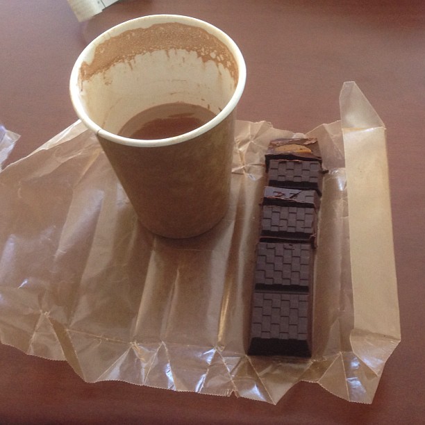 a cup of coffee next to a small chocolate bar