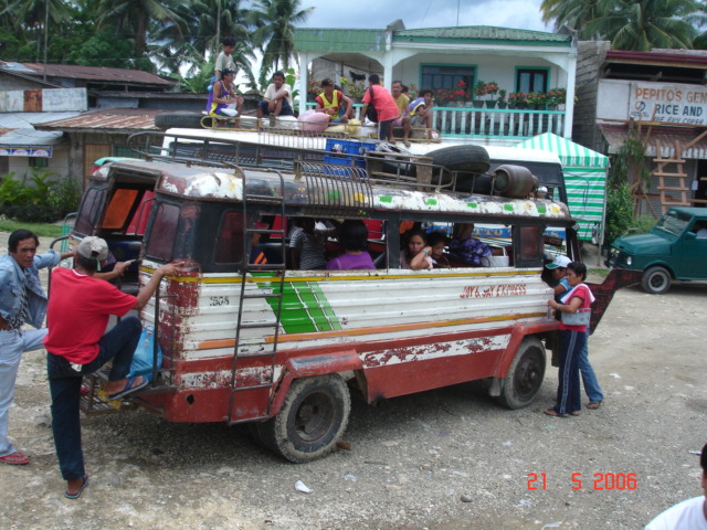 several people stand outside an old bus