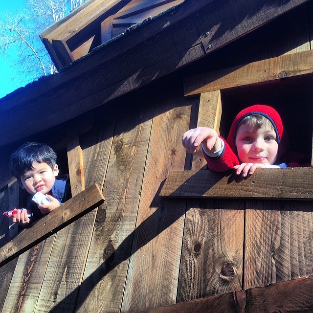 two children are standing in the window of a wooden structure