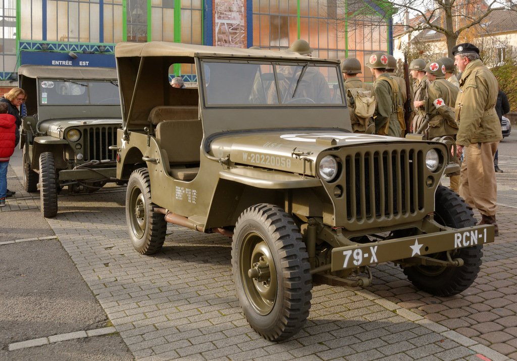 an army jeep with some military officers standing in front of it