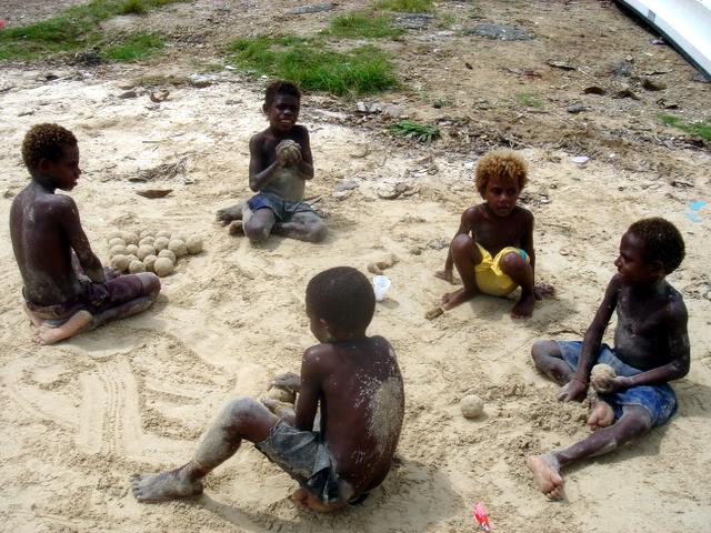 four children play in the sand together