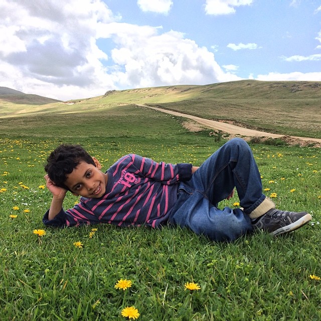 a boy laying in the grass smiling