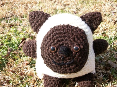 a small crocheted panda bear laying in grass