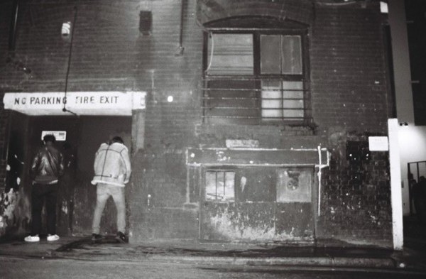 two people standing in front of a rundown building at night
