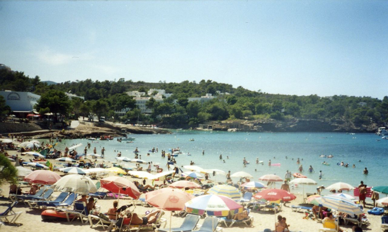 a bunch of people are on the beach and some have umbrellas