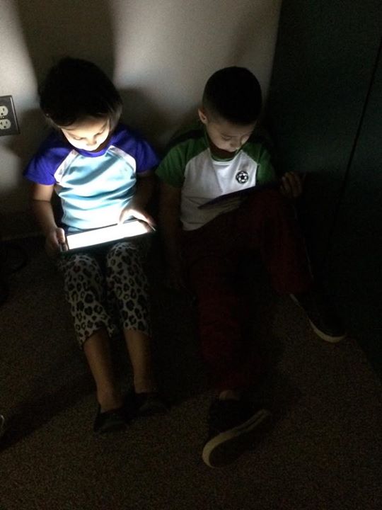 two children sitting in a room looking at a light