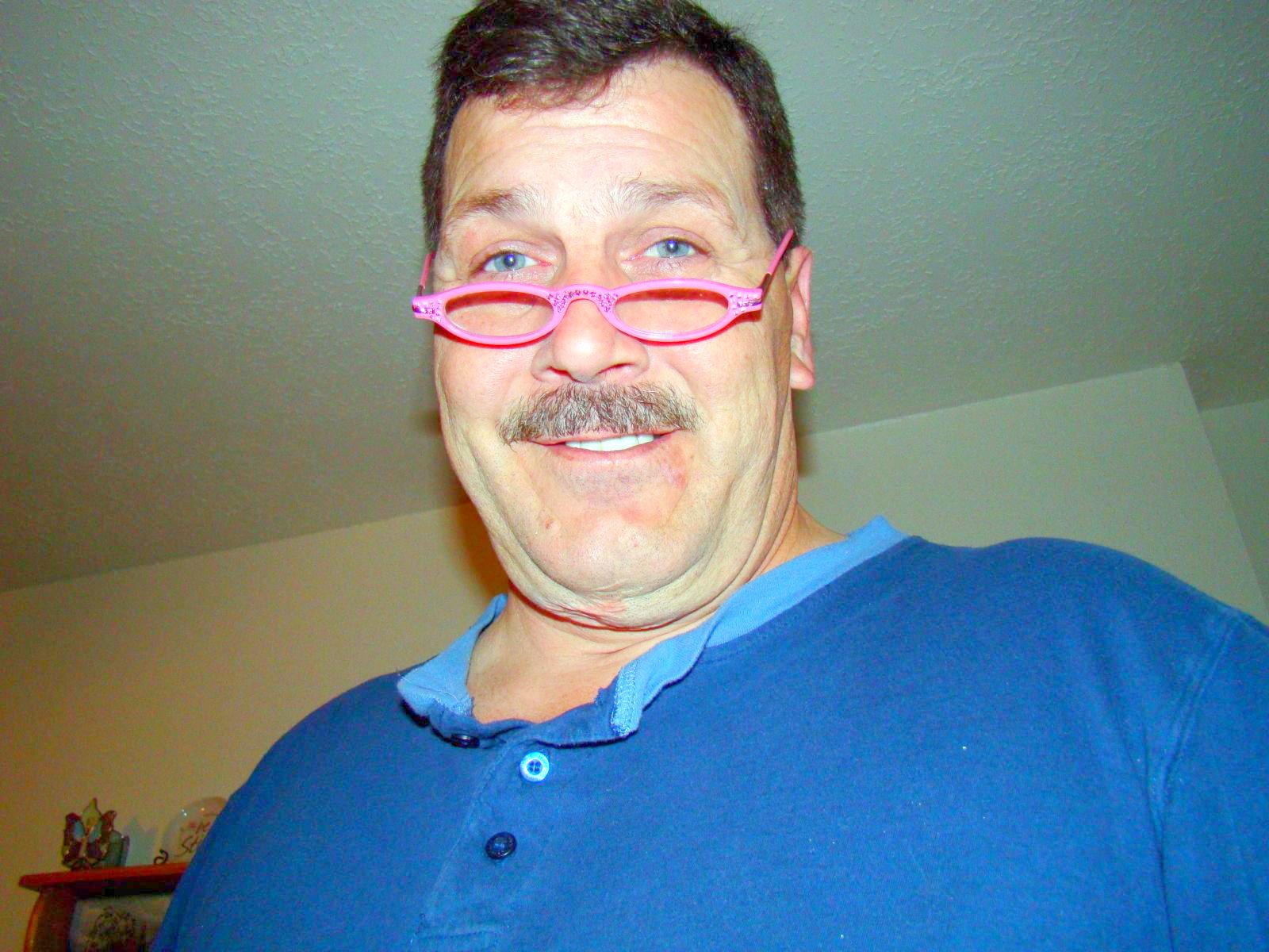 a man with bright pink glasses smiling for the camera