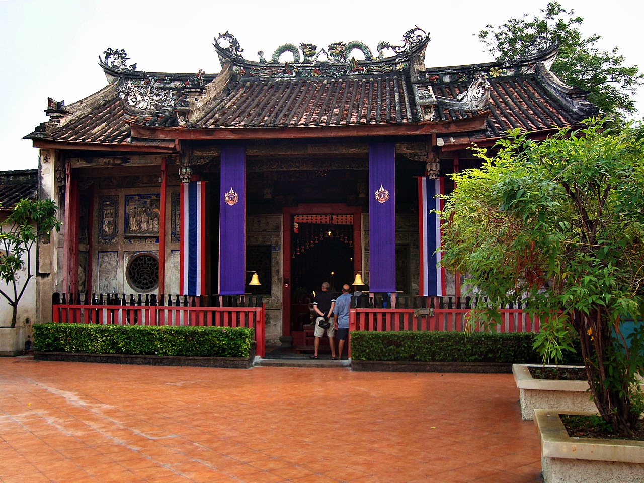 a man stands in front of an asian - styled building with purple accents