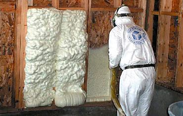 worker in protective clothing looking through the insulation wall of his home