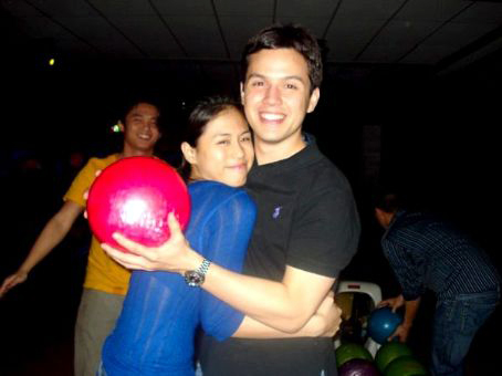 a man and woman standing next to each other holding up bowling balls