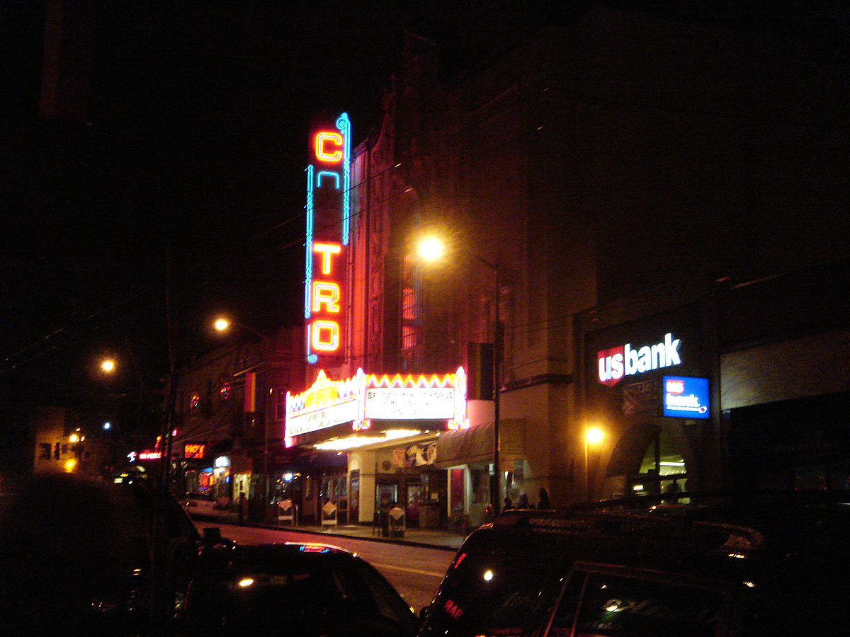 a theater with cars parked on the street at night