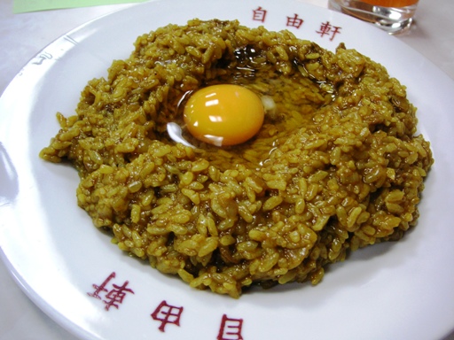 an egg in a fried meaty dish, with chinese writing below it