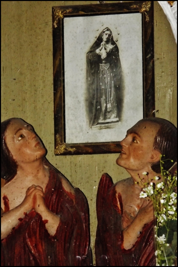an artistic religious statue of two people next to a framed po