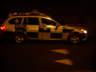 a small white police car parked on the side of a road at night